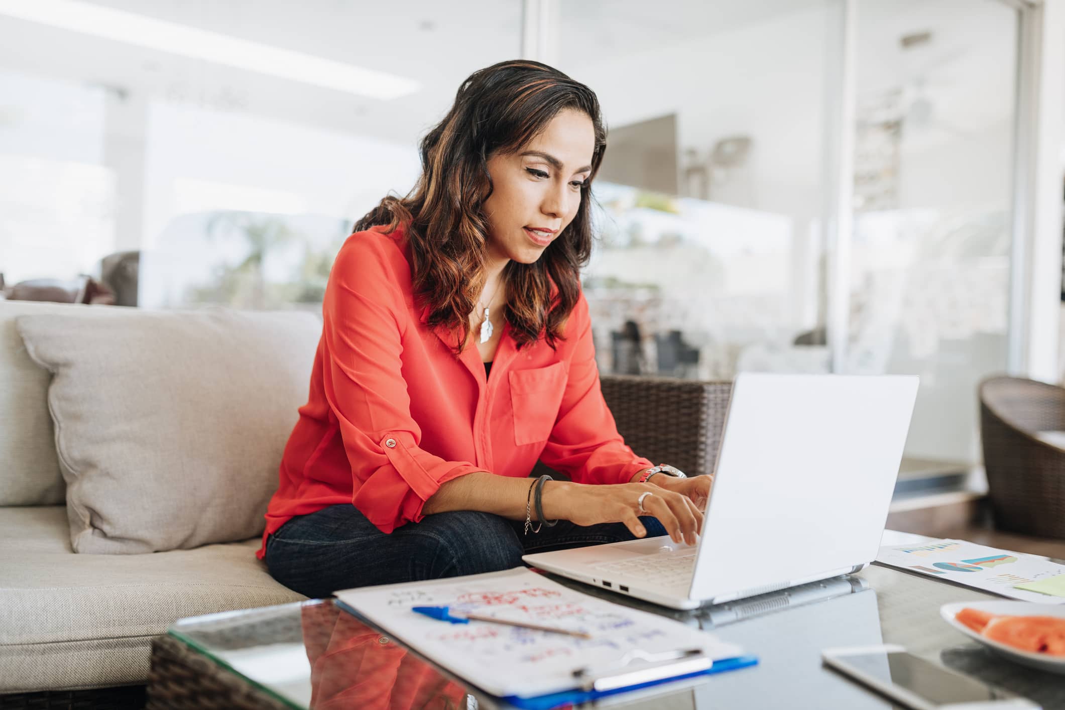 Travel nurse wearing red blouse sitting at her table typing on her laptop. Travel nurse wearing red blouse sitting at her table typing on her laptop.