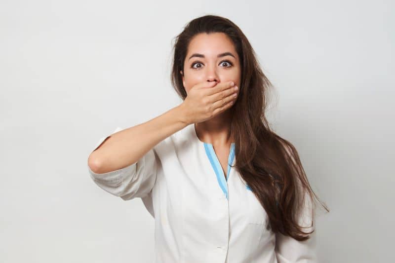 Young nurse doctor covering mouth with hand for mistake. Young nurse doctor covering mouth with hand for mistake.