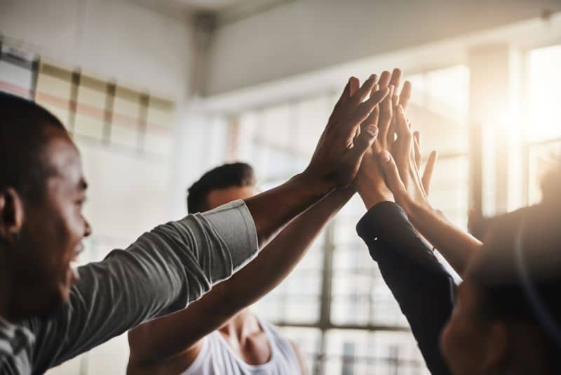 A group of men and women giving each other a high five. A group of men and women giving each other a high five.