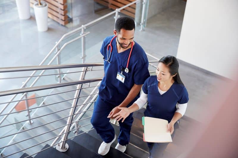 Two healthcare colleagues talking on the stairs at hospital Two healthcare colleagues talking on the stairs at hospital