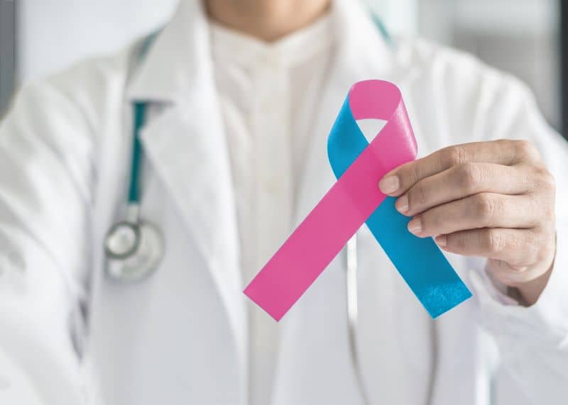 Doctor holding a pink and blue ribbon, symbolic of sudden infant death syndrome. Doctor holding a pink and blue ribbon, symbolic of sudden infant death syndrome.