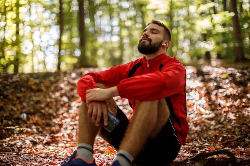Portrait of relaxed young man with bluetooth headphones in forest Portrait of relaxed young man with bluetooth headphones in forest