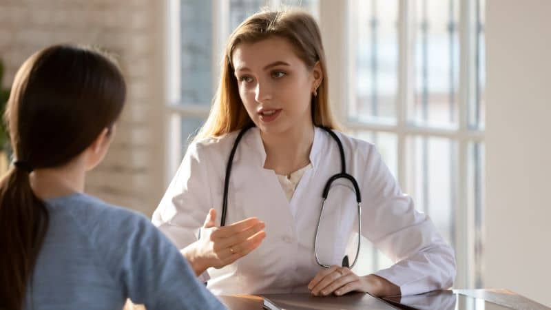 A young doctor converses with female patient. A young doctor converses with female patient.