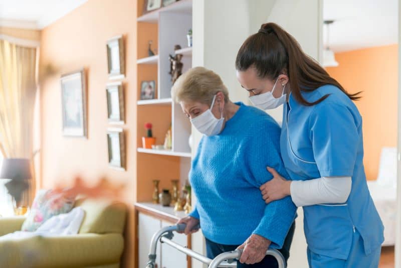 Home caregiver wearing a facemask while assisting a senior woman Home caregiver wearing a facemask while assisting a senior woman