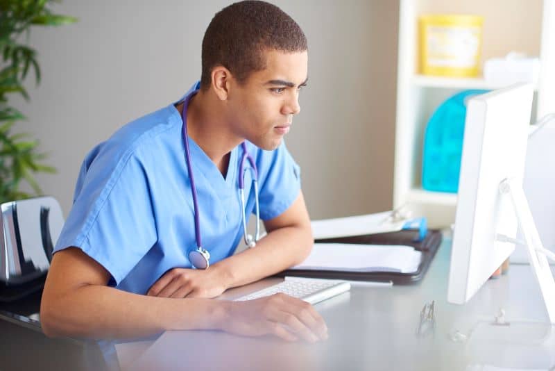 Male doctor views content on PC. Male doctor views content on PC.
