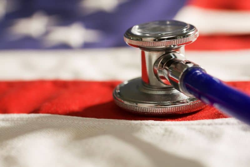 A close-up of a stethoscope resting on a the cloth fabric of the United States flag A close-up of a stethoscope resting on a the cloth fabric of the United States flag
