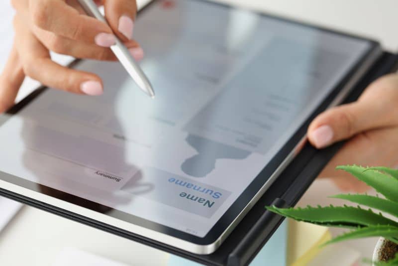 Woman fills out electronic resume form on tablet to find job. Woman fills out electronic resume form on tablet to find job.
