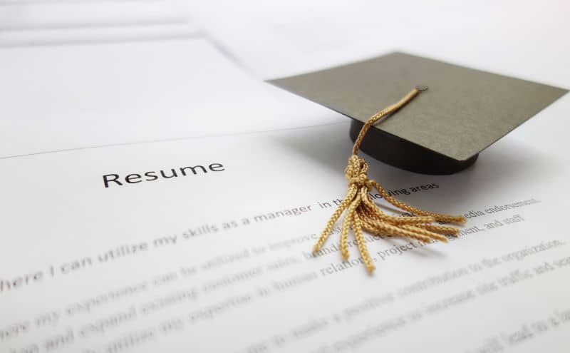 Small graduation cap on a resume . Small graduation cap on a resume .