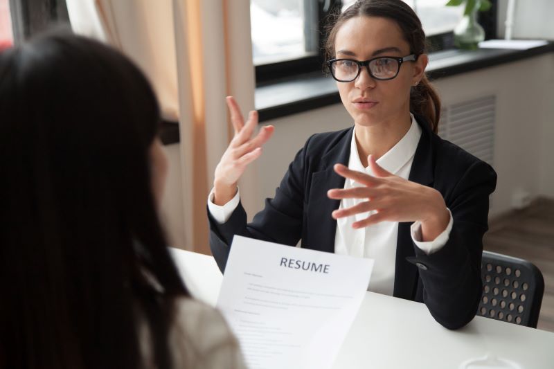 Confident millennial female applicant in glasses talking at job interview. Confident millennial female applicant in glasses talking at job interview.