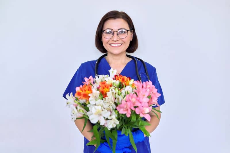 A healthcare professional holding a bouquet of flowers. A healthcare professional holding a bouquet of flowers.