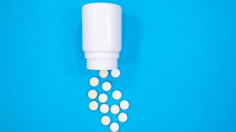 Pills spilling out of pill bottle and isolated on blue. Pills spilling out of pill bottle and isolated on blue.