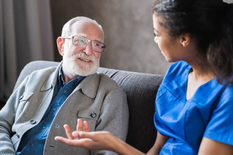 A young female nurse converses with her elderly male patient. A young female nurse converses with her elderly male patient.