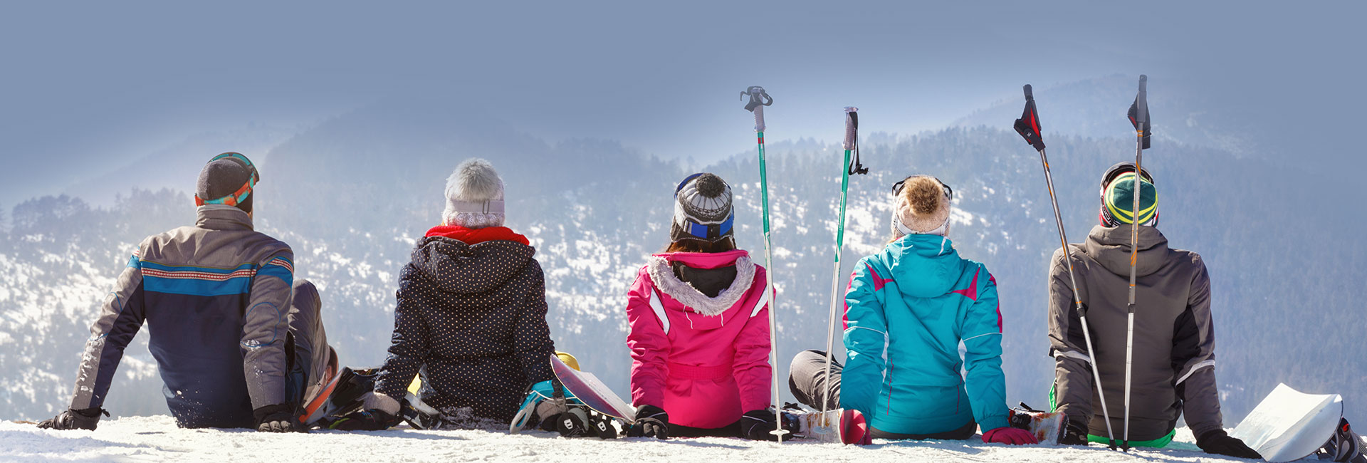 Five travel nurses wearing ski attire and holding skis overlooking the snowy slopes.