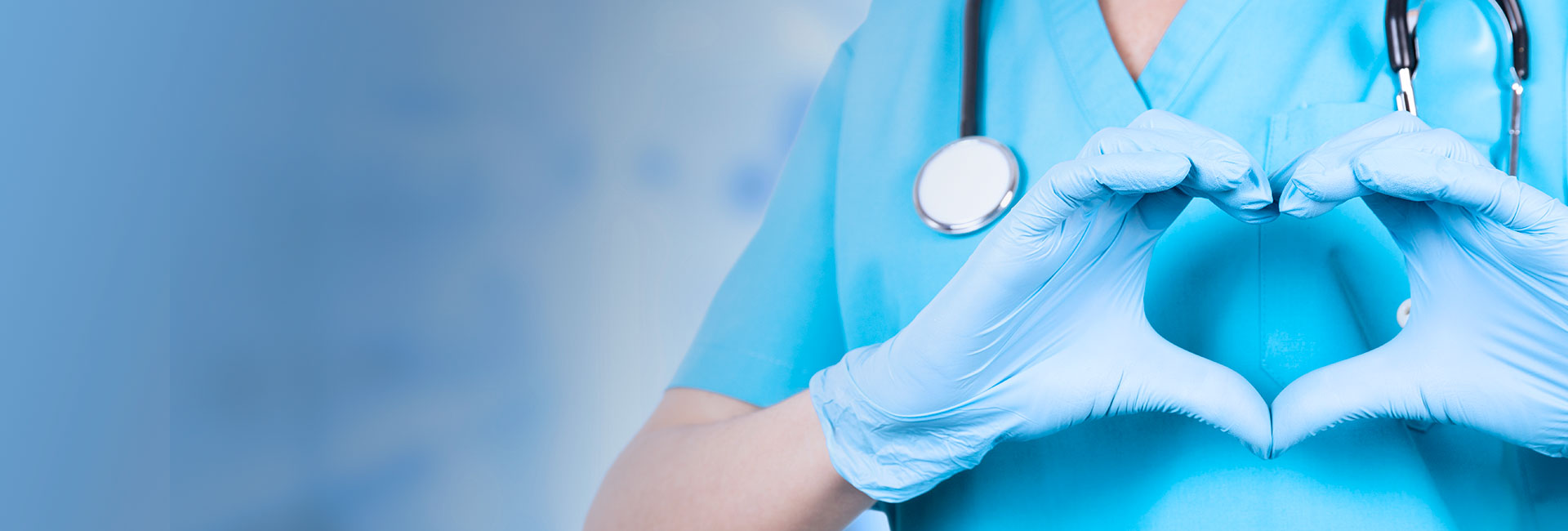 Nurse wearing blue gloves holding her hands in the shape of a heart.